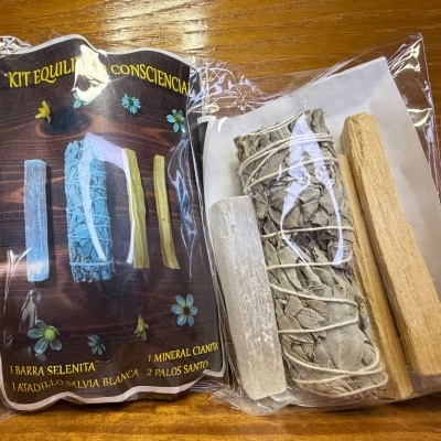 Kit de purificação com vários itens naturais embalados em plástico sobre mesa de madeira.
