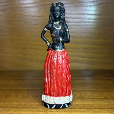 Estátua de mulher com saia vermelha sobre superfície de madeira clara