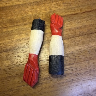 Pendurantes em forma de braços de madeira pintada em vermelho, branco e preto.