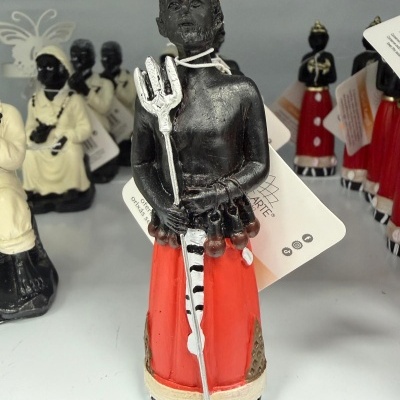 Estátua decorativa de figura masculina com tridente e roupa vermelha.