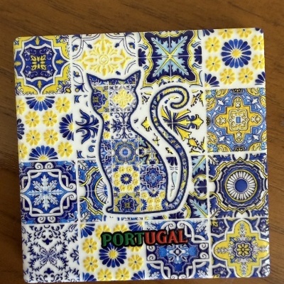 Azulejo decorativo azul, amarelo e branco com forma de gato e palavra PORTUGAL