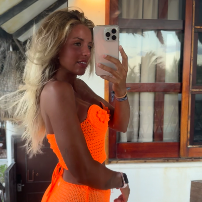 Roupa feminina de malha laranja neon feita à mão em ambiente com janela de madeira.