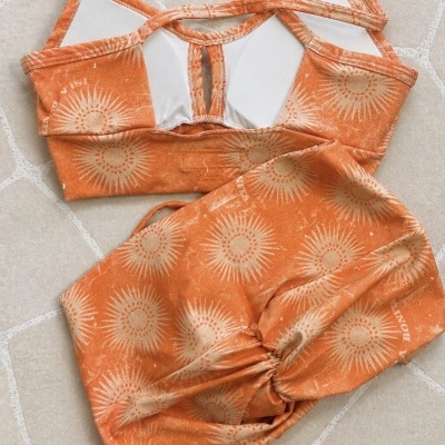 Conjunto desportivo laranja com padrão de sol bege em tecido macio