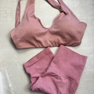 Conjunto desportivo rosa com soutien e leggings sobre fundo cinzento