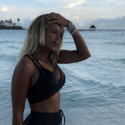 Mulher com top e leggings pretas na praia com pulseiras e relógio branco