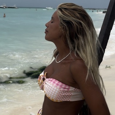 Biquíni xadrez rosa, branco e amarelo numa mulher junto à praia e mar. 