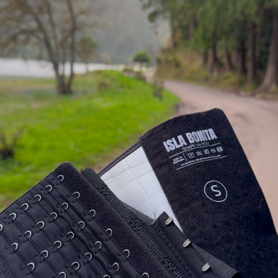 Cinta modeladora preta com fechos de gancho e etiqueta com texto ISLA BONITA, segurada ao ar livre