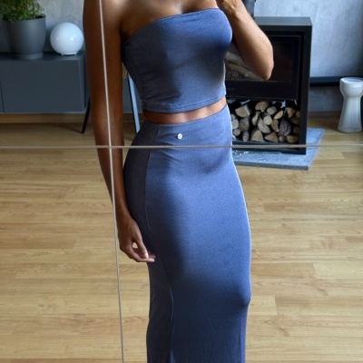 Conjunto feminino azul com top sem alças e saia longa em ambiente interior