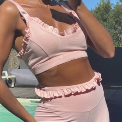 Conjunto desportivo feminino cor-de-rosa com folhos junto a piscina