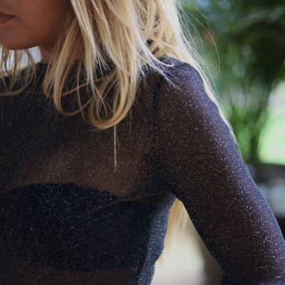 Camisola preta brilhante transparente de manga comprida em mulher loira