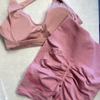 Conjunto desportivo cor-de-rosa com top e leggings sobre superfície clara