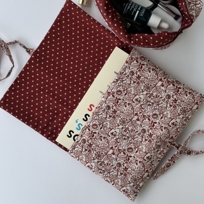 Estojo ou bolsa de tecido com padrão floral castanho e bege e interior castanho com florzinhas brancas, com frascos e pincéis de beleza visíveis