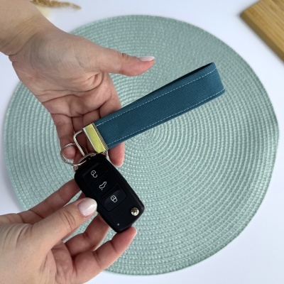 Chave de carro preta com porta-chaves azul nas mãos