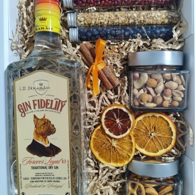 Conjunto de gin, especiarias e snacks em caixa branca com enchimento de papel.