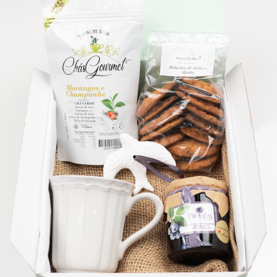 Conjunto de chá com chávena branca, chá em saco branco, bolachas e compota em caixa branca