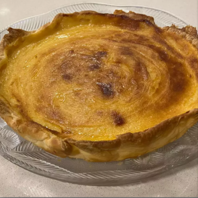 Tarte caseira de massa folhada com recheio amarelo em prato transparente