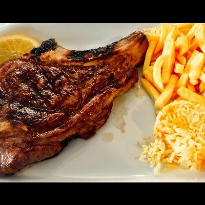 Bife grelhado com batatas fritas e arroz num prato branco, com uma rodela de limão