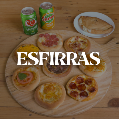 Mini esfirras variadas, latas de refrigerante Go Guaraná e Sumol Laranja, e esfirra maior numa mesa de madeira