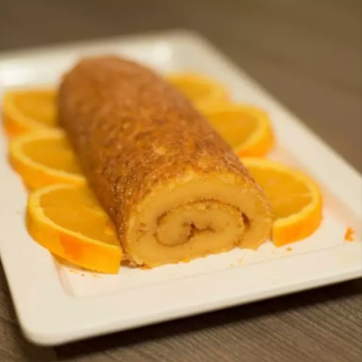 Rolo de bolo com fatias de laranja e prato branco