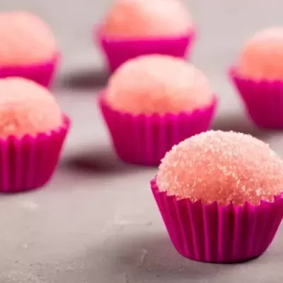 Seis doces rosa em forminhas de papel rosa sobre superfície cinza
