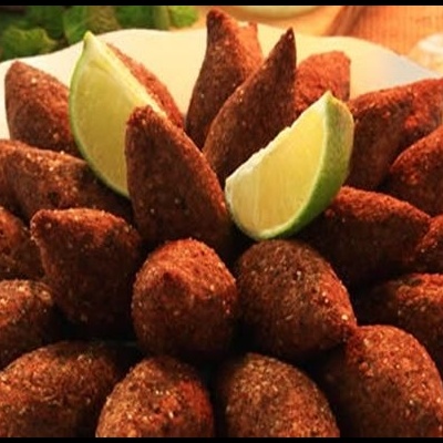 Prato branco com kibes fritos dispostos em círculo e pedaços de limão no centro