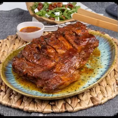 Costeletas grelhadas com molho num prato azul e castanho com base de fibras naturais