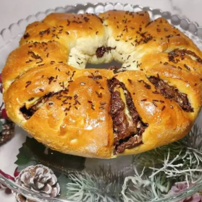 Pão doce circular recheado com chocolate e granulados num prato de vidro