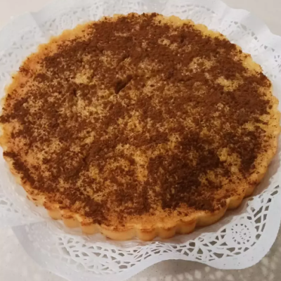Tarte redonda com canela em pó sobre toalha branca rendada