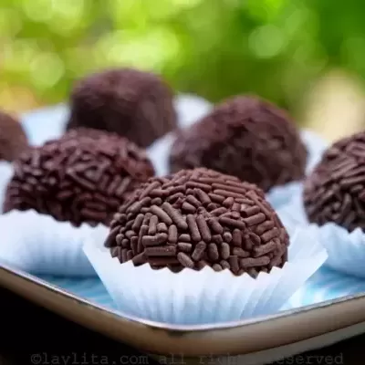 brigadeiros cobertos com granulados de chocolate em forminhas azuis sobre bandeja