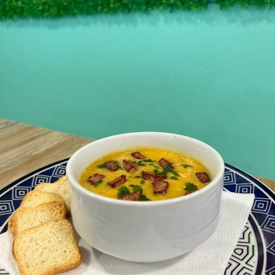 Sopa com bacon e pão torrado sobre prato azul e guardanapo branco