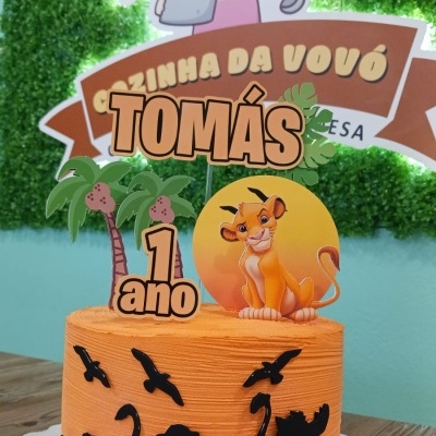 Bolo de aniversário laranja com decoração do Rei Leão e texto TOMÁS 1 ano