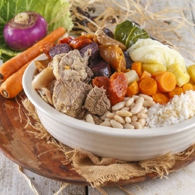 Prato com cozido tradicional português em prato branco sobre prato de madeira