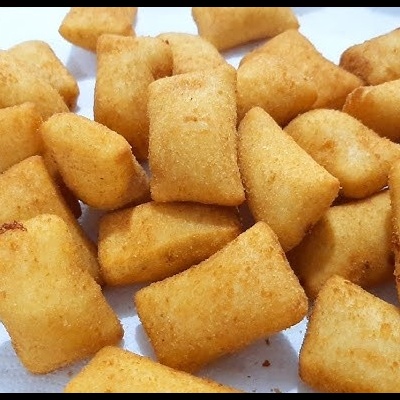 Salgadinhos fritos dourados em forma de pequenos retângulos sobre superfície branca