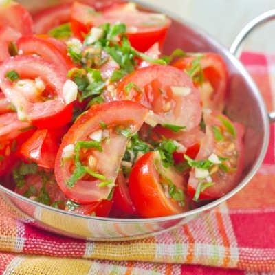 Salada de tomate com coentros e cebola em recipiente metálico