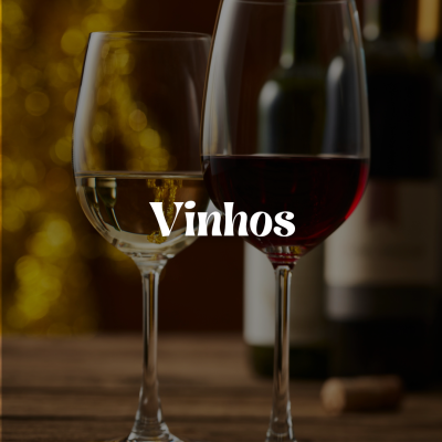 Duas taças de vinho, uma com vinho branco e outra com vinho tinto, sobre uma mesa de madeira.