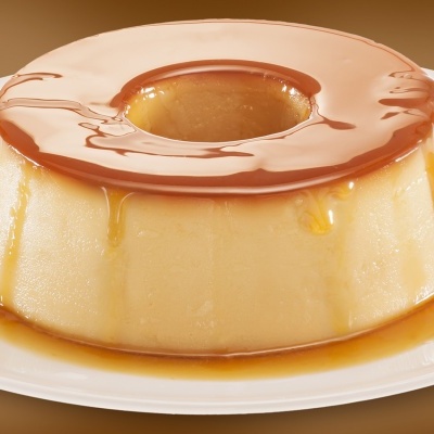 Pudim de caramelo em prato branco com cobertura brilhante de caramelo