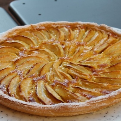 Tarte de maçã com fatias caramelizadas e borda polvilhada de açúcar em pó