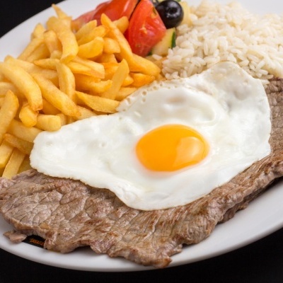Prato com bife, ovo estrelado, batatas fritas, arroz e salada