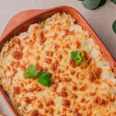 Lasanha gratinada em tabuleiro de barro com folhas de salsa