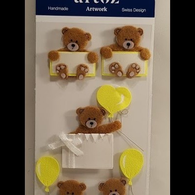 Cartela de ursinhos de tecido com balões amarelos e placas brancas, em embalagem com topo azul e texto artoz