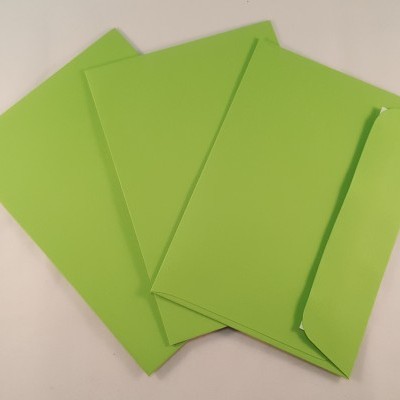 Quatro envelopes verdes de papel, um aberto, sobre uma superfície branca