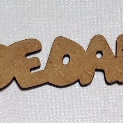 Palavra 'DECOAL' recortada em cortiça sobre tecido branco