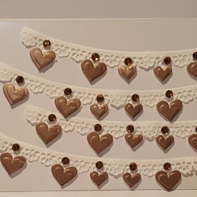 quatro linhas de colares com corações castanho metálico em fita branca rendada