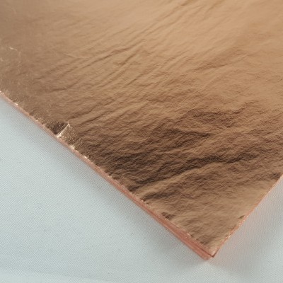 Folha metálica cor cobre com textura branca de fundo.