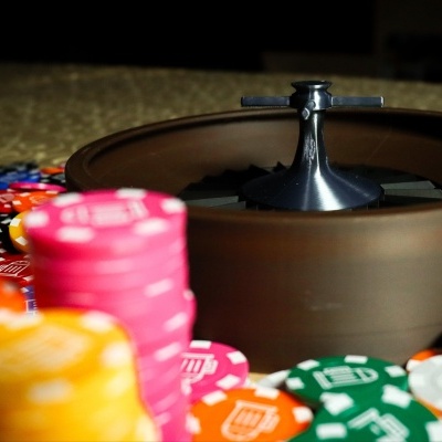 Brown roulette wheel with silver spindle and colorful casino chips around it