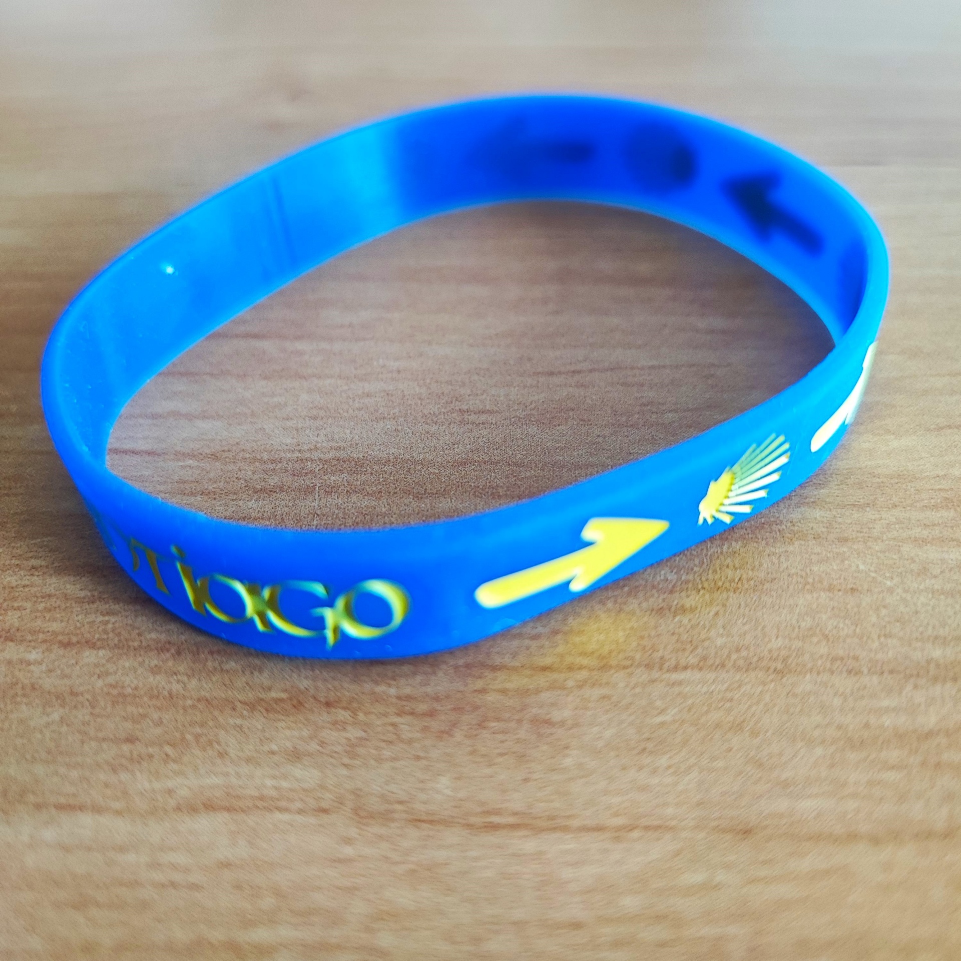Pulseira (borracha) Pulseira em silicone azul com seta e concha amarelas sobre madeira clara