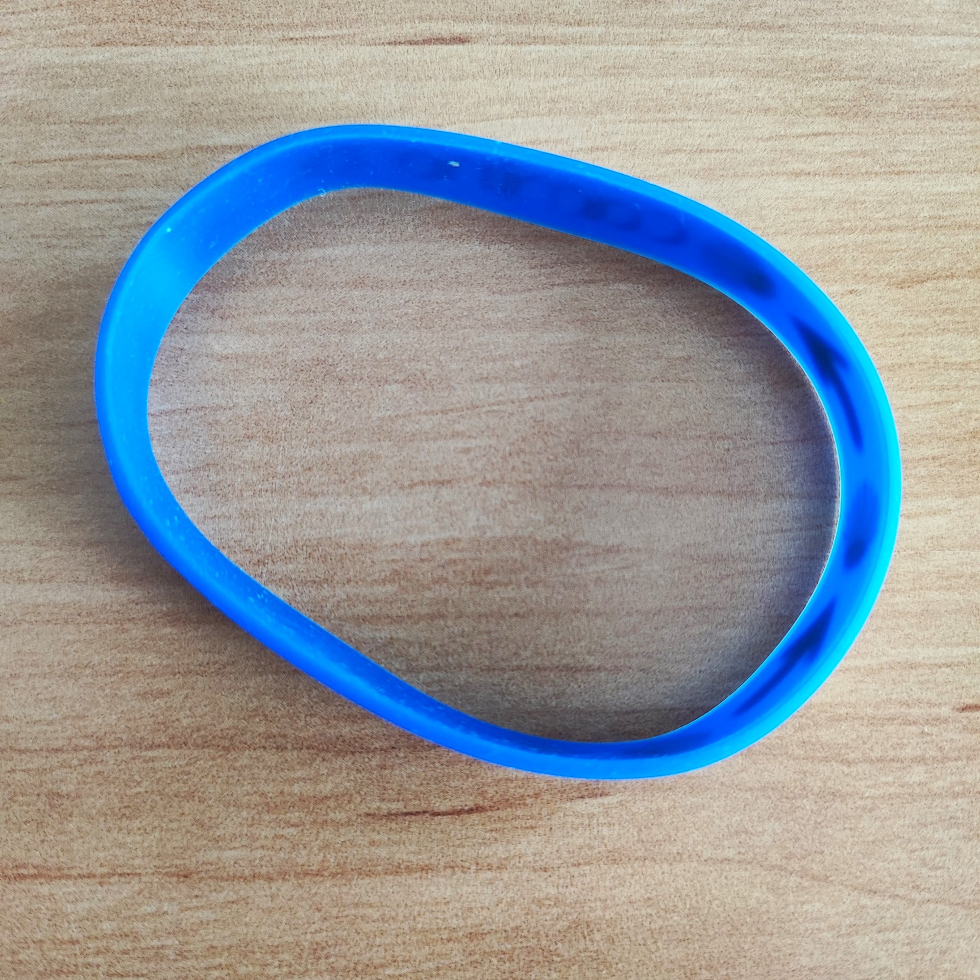 Pulseira (borracha) Pulseira de silicone azul oval sobre madeira clara