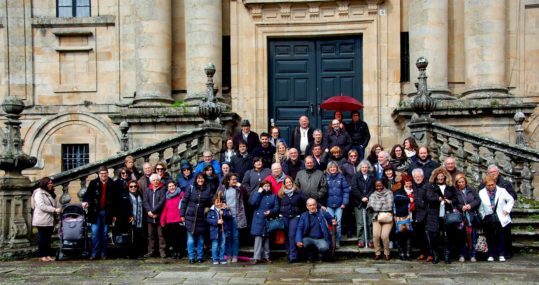 Grande grupo de pessoas em escadaria de edifício histórico com porta escura