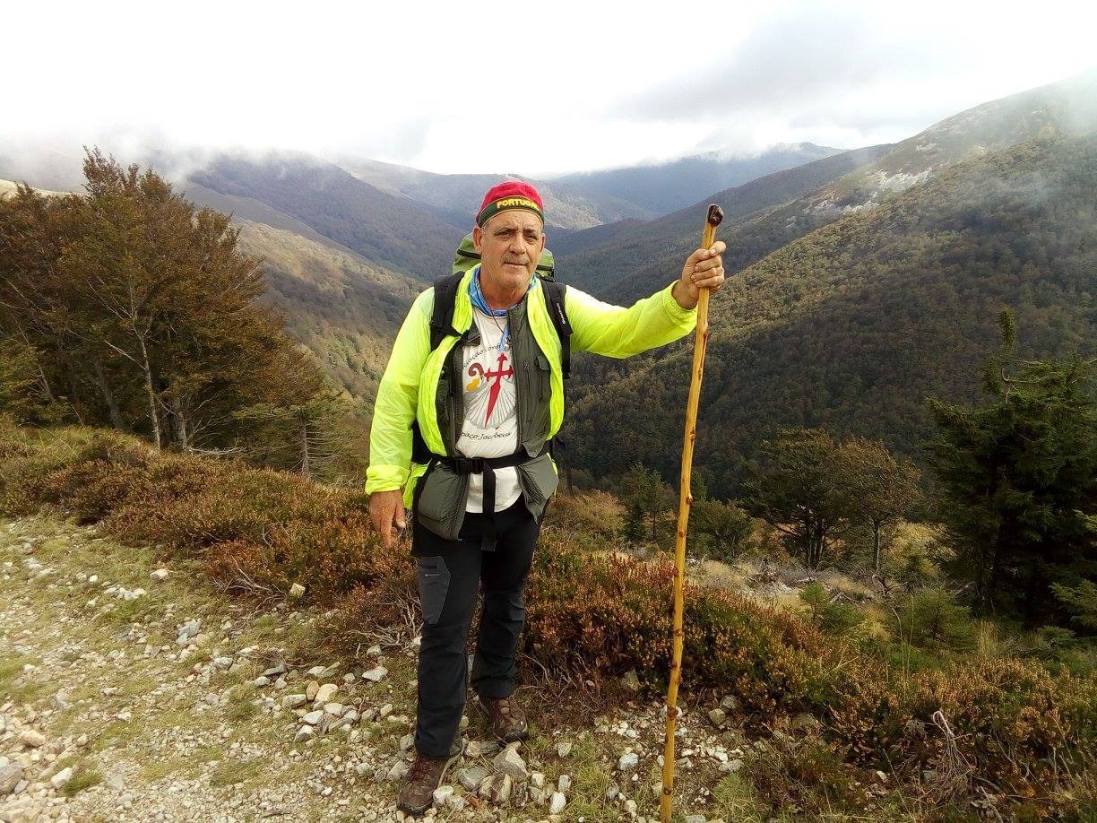 Homem com roupa de caminhada e bastão numa trilha de montanha