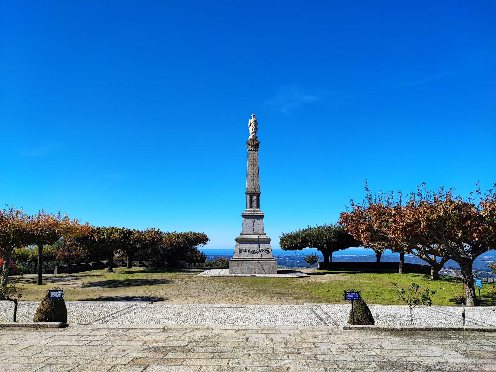 A variante da Franqueira Monumento de pedra com estátua num passeio com árvores e céu azul
